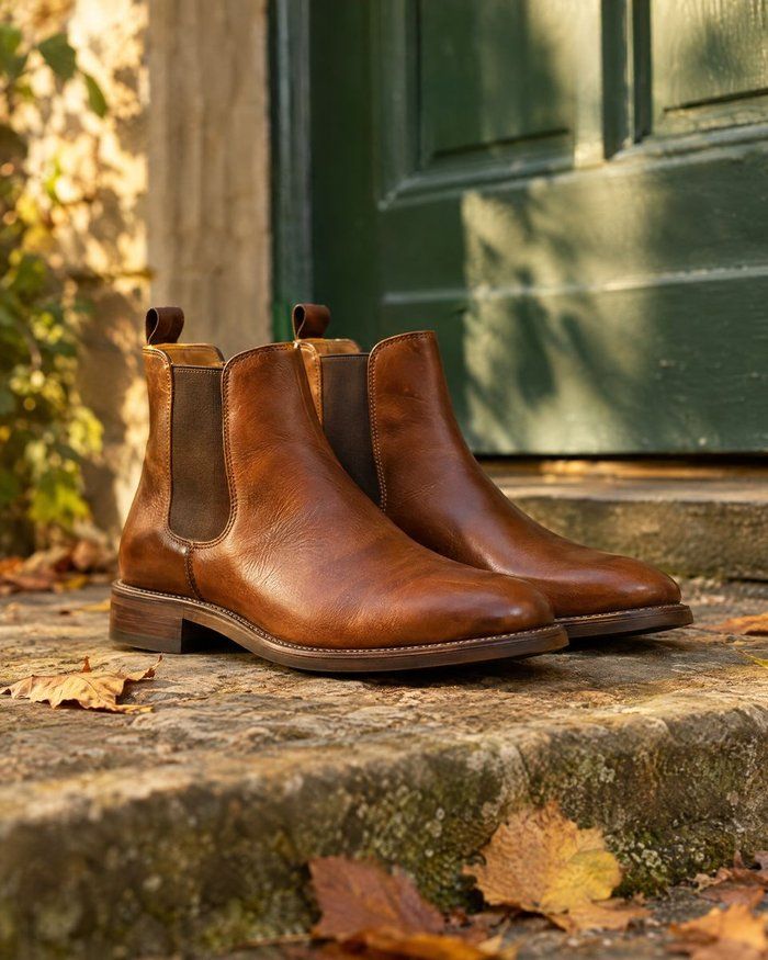 Tan Chelsea boots on a stone step in front of a green door.